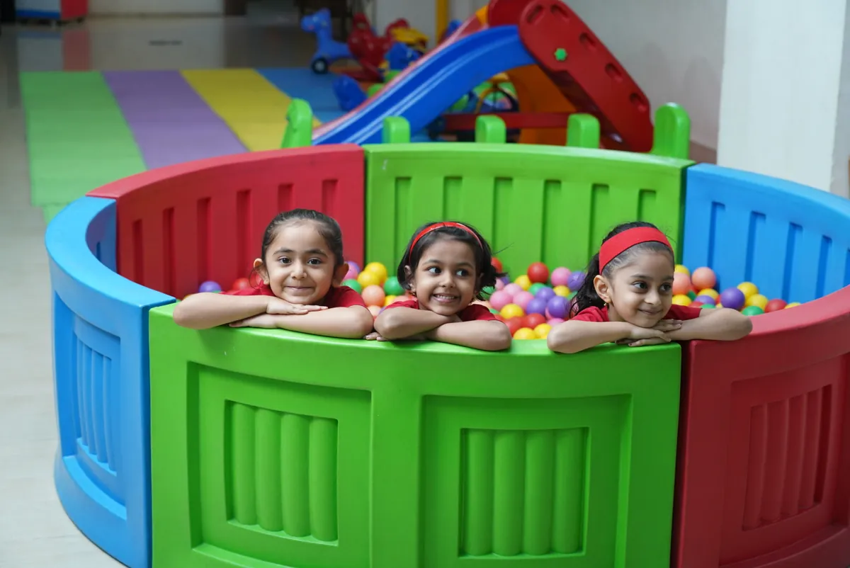 Three children smiling at an indoor ball pit