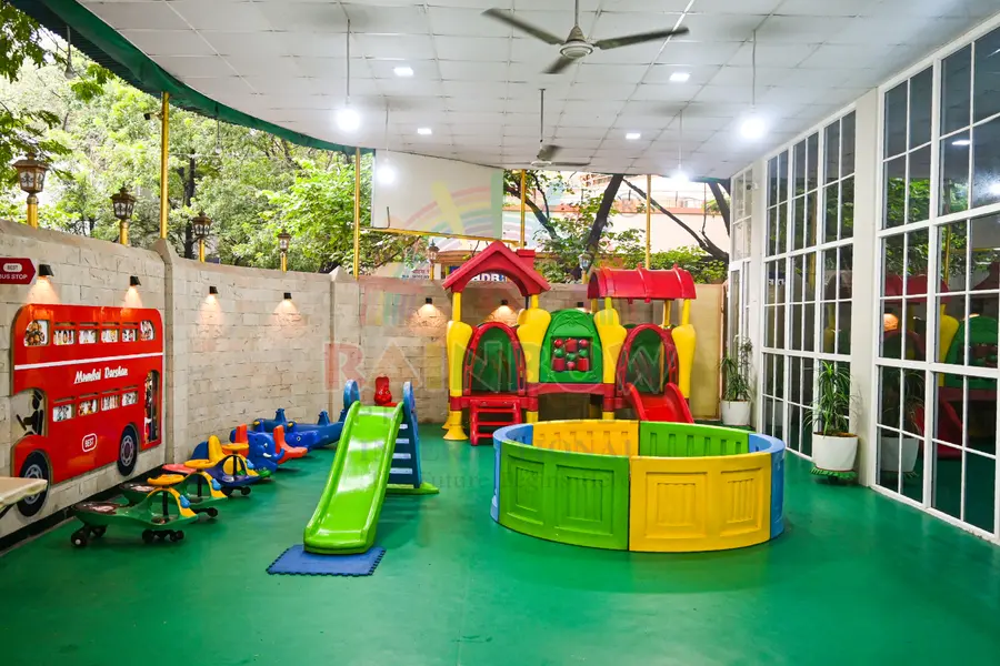 Slide, playhouse and toys in a covered Rainbow playgroup area