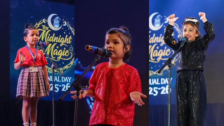 Three children performing on stage at a Rainbow preschool annual day