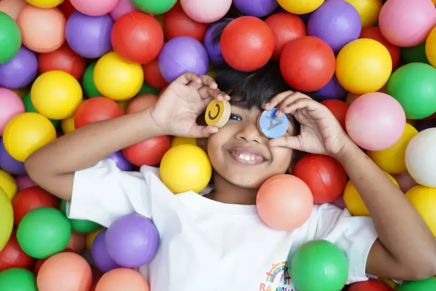 Child smiling among colourful balls in an indoor play area