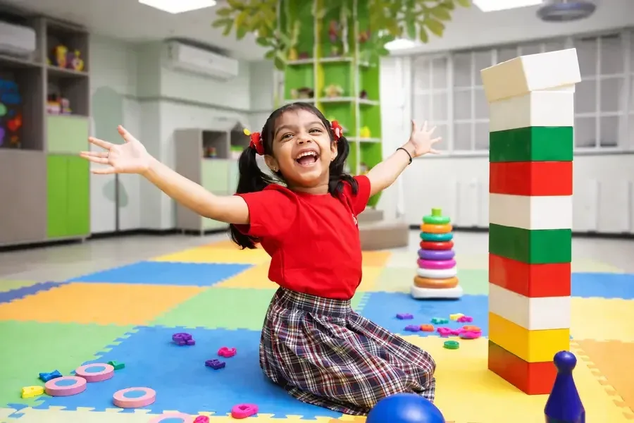 Child playing with colourful rings and foam blocks in a classroom activity area