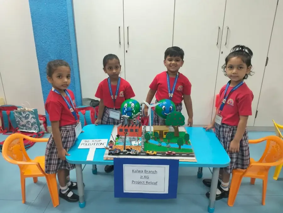 Four children showing colourful projects at a classroom table