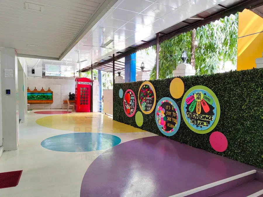 Bright indoor play corridor with colourful floor circles and a children's display wall