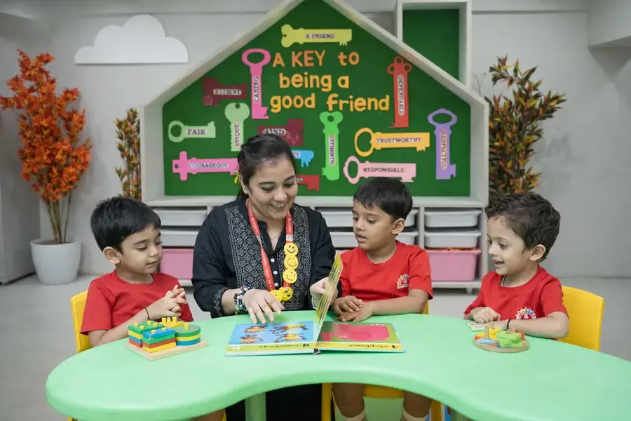 Teacher guiding three children at a classroom activity table