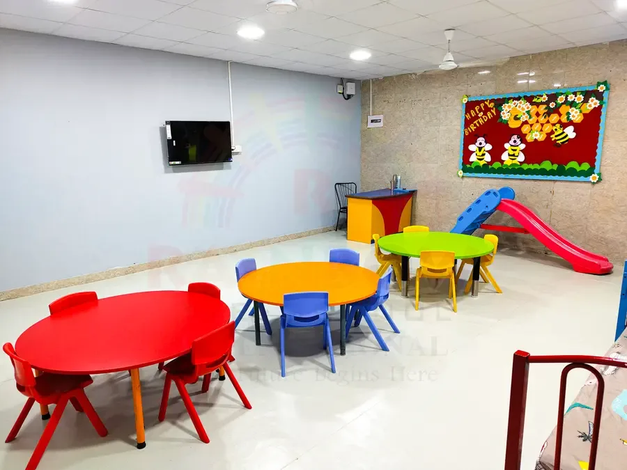 Preschool activity room with colourful child-sized tables and a wall display
