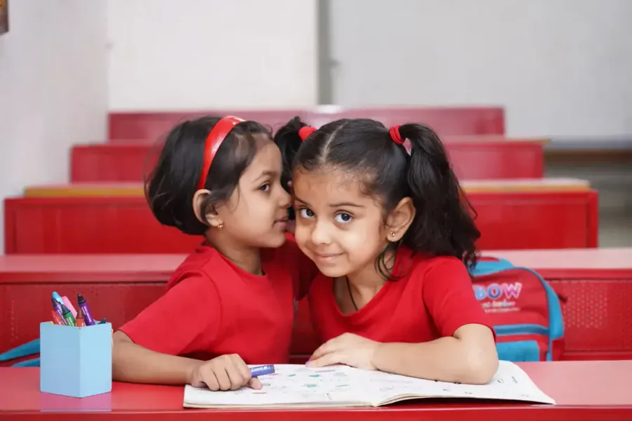Two children drawing together at a classroom table