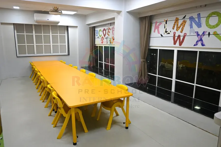 Yellow child-sized tables and chairs in a Rainbow Preschool classroom